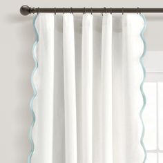 white curtains with blue scalloped trim hanging on a curtain rod