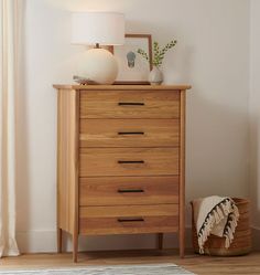 a wooden dresser sitting next to a lamp on top of a hard wood floor