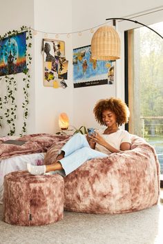 a woman is sitting on a bean bag chair in her living room reading a book