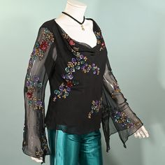 Vintage sheer black silk angel sleeve blouse with sequin & beaded flowers.  Cowl neckline, pullover top. Relaxed fit at the waist.  SIZE:  All sizing given is approximate. Refer to measurements for an accurate fit. Shoulder: 17" Underarm: 42" Sleeve: 24 3/4" Waist: 37" Length: 21" Mannequin measurements:   Size 2, Bust - 33"   Waist - 24"   Hips - 34" CONDITION:  Very good COLOR: Black, multicolored sequins & beads.  MATERIAL: silk chiffon, sequins, beads.  CARE: Dry clean.  We try to give very accurate descriptions for each item. We are a smoke-free environment. Domestic Shipping: Priority Mail including free tracking and insurance. Upon request - International Shipping: First Class including tracking & insurance as available. FINAL SALE. Accessories not included in the sale, they are for Silk Party Tops With Sequins, Festive Silk Top With Sequins, Silk Embellished Party Top, Festive Silk Sequin Top, Glamorous Silk Top With Sequins, Glamorous Silk Sequined Top, Glamorous Sequined Silk Top, Festive Long Sleeve Tops For Night Out, Glamorous Long Sleeve Silk Tops