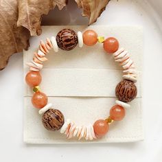 This bohemian retro style bracelet is adorned with a medley of natural coconut shell and smooth burnt orange Aventurine gemstone beads, each exuding the warmth of tropical sunshine. -10mm Orange Aventurine Gemstone Beads and Sea Shell Chips -14mm Genuine Coconut Shell Beads -4mm Gold Spacer Beads -Creamy White Turquoise Spacer Beads -Beautifully Packaged to be Gift Ready -Free Jewellery Pouch  B R A C E L E T * S I Z E *Measure your wrist using a tape measure (or a piece of string and ruler) ACTUAL Wrist Size * X Small 15-16 cm * Small 16-17cm * Medium 17-18cm * Large 19-20cm *If you are unsure of size  - Medium fits most wrists *Bracelet size will be approximatly 2cm longer than ACTUAL wrist size for a comfortable fit. Need a CUSTOM size ? *If you need a custom size of this listing -  sel Orange Aventurine, Jewellery Pouch, Shell Bracelet, White Turquoise, Coconut Shell, Unisex Jewelry, Shell Beads, Handmade Boho, Tape Measure