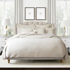 a white bed sitting in a bedroom next to two framed pictures on the wall above it