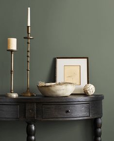 a table with a bowl and two candles on it, next to a framed photograph