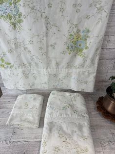 a white sheet with flowers on it next to a potted plant