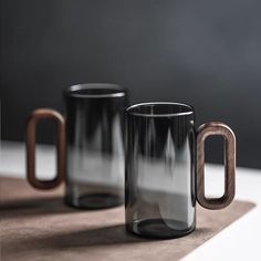 two black and brown coffee mugs sitting next to each other on top of a table