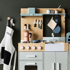 a toy kitchen with wooden cabinets and accessories