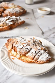 a white plate topped with pastry covered in powdered sugar on top of a table