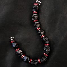 "If you're like me, you love skulls. So show your love with this skull bracelet! This bracelet features black howlite stone skulls and red stone crystal spacers, and is closed with a silver stainless steel lobster claw clasp. It comes in 3 sizes: Large - Fits wrists you to 7 1/2\" around Medium - Fits wrists up to 6 1/2\" around Small - Fits wrists up to 5 1/2\" around. If you need a different size, let me know and I will see what I can do. Make sure to check out my shop, PopBangBoom, for all so Black Gothic Skull Bracelet, Black Gothic Bracelets With Skull Print, Adjustable Black Punk Beaded Bracelets, Adjustable Black Beaded Punk Bracelets, Black Beaded Gothic Bracelets, Gothic Black Beaded Bracelets, Punk Style Black Beaded Bracelets For Gift, Emo Black Skull Jewelry, Gothic Black Beaded Bracelets For Halloween