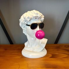 a white busturine with sunglasses and a pink bubble in it's mouth