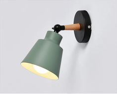 a green wall light with a wooden arm and black base, on a white wall