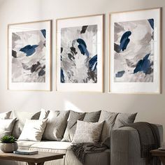 three paintings hang on the wall above a couch and coffee table in a living room