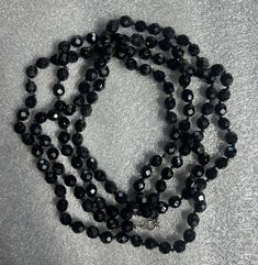 Make a statement with this stunning Vintage Opera Length Necklace featuring large black faceted hematite beads. The elegant opera length adds a touch of sophistication to any outfit, while the faceted hematite beads catch the light for added sparkle and glamour. Perfect for both casual and formal occasions, this necklace is a timeless piece that will elevate your style with its classic beauty. Necklace measures approximately 60 inches long when unclasped. Elegant Hematite Beaded Necklaces, Black Faceted Beaded Necklaces For Party, Formal Black Faceted Beaded Necklaces, Formal Black Faceted Beaded Necklace, Formal Black Beaded Necklace With Faceted Beads, Black Faceted Jewelry For Party, Black Beaded Necklace With Faceted Beads For Evening, Elegant Black Faceted Beads, Faceted Beaded Necklaces For Party