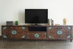 a tv is sitting on top of a wooden entertainment center with blue flowers and leaves painted on it