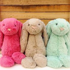 three different colored stuffed animals sitting next to each other