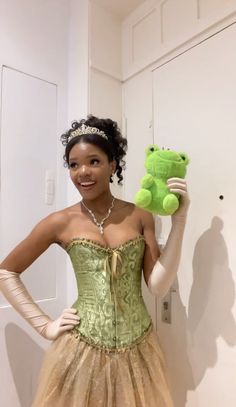 a woman in a dress holding a green teddy bear