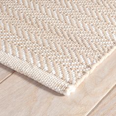 a close up view of a white rug on a wooden floor with wood grains