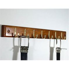 a wooden coat rack with four hooks and two leather belts hanging from it's sides