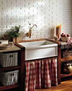 a kitchen sink with red and white checkered curtains in front of it, next to a window