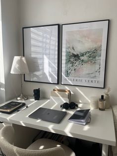 a white desk topped with a laptop computer next to a lamp and pictures on the wall