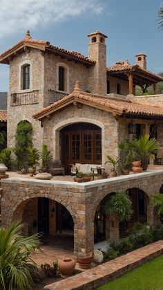 a large stone house with lots of greenery and potted plants on the front