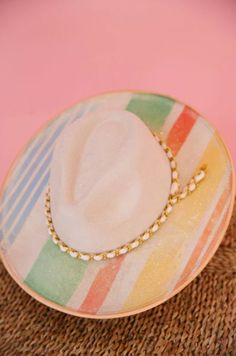 Add a splash of color with our Cabana Girl Rancher Hat. In cream with a playful rainbow stripes design and a gold band, this unique hat will make you stand out from the crowd. Perfect for sunny days at the beach or lounging by the pool! White Summer Hat Bands For Vacation, White Flat Brim Felt Hat For Summer, White Bohemian Boater Hat With Flat Brim, White Short Brim Fedora For Beach Season, White Brimmed Felt Hat For Summer, White Felt Hat With Short Brim For Summer, White Curved Brim Fedora For Beach Season, White Fedora With Curved Brim For Beach Season, Multicolor Hat For Beach And Kentucky Derby