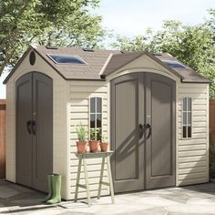 a garden shed with two potted plants on the side