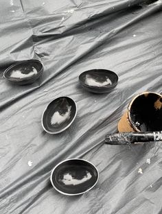 black and white photograph of empty plates on tarp with paintbrush in the foreground