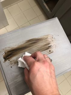 a person wiping off some brown paint on a piece of wood