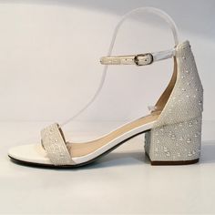 a pair of white high heeled shoes with beading on the ankle and straps