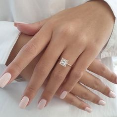 a woman's hand with pink manicured nails and a diamond ring