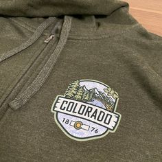 A hooded sweatshirt version of our 2023 best selling Woodland t-shirt, this Colorado hoodie is an awesome combination of organic outdoor colors and ColoradoCool's bold design style. Features a sweet outdoor Colorado landscape, big "COLORADO" text, Colorado's established date and a nice subtle topo map in the background. The smaller design on the front is perfect for those who like to put into practice a little bit of that "mullet approach", business in the front and party in the back. Snag this Outdoor Fleece Hoodie Tops, Urban Hoodie With Relaxed Fit For Outdoor, Urban Hoodie Sweatshirt For Outdoor, Urban Style Hoodie Sweatshirt For Outdoors, Casual Cotton Hoodie For Outdoor Activities, Urban Relaxed Fit Sweatshirt For Outdoor, Outdoor Fleece Top With Adjustable Hood, Urban Hoodie For Outdoor Activities In Fall, Urban Hooded Sweatshirt For Outdoor Activities