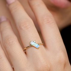 a woman's hand with a gold ring and opalite stone on it