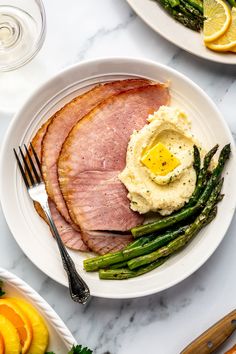 ham, mashed potatoes and asparagus on a white plate with silverware