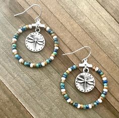 These tan and turquoise seed bead hoops are so pretty! The colors of blue and white are also present.  The dragonfly dangling from the mddle gives these hoops character.  They are the perfect dangling hoop earrings.  These hoops are 30 mm (1.1/8 inches) in diameter and very light on the ears.  These handmade lovelies would be great as a gift or something for you to treat yourself with. ~I use high quality hypoallergenic materials along with many different glass seed beads.  I work hard to create Handmade Turquoise Hoop Earrings For Beach, Bohemian Heishi Beads Small Hoop Earrings, Bohemian Heishi Beads Hoop Earrings, Nickel-free Small Hoop Beaded Earrings For Summer, Bohemian Small Hoop Heishi Bead Earrings, Bohemian Turquoise Hoop Earrings For Beach, Turquoise Bohemian Hoop Earrings For Beach, Adjustable Heishi Beads Earrings For Beach, Bohemian Hoop Beaded Earrings With Heishi Beads