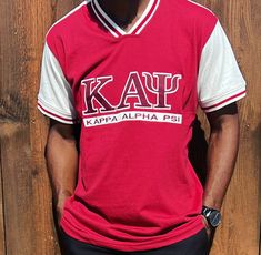 Show off your loyalty and pride for Kappa Alpha Psi fraternity with this stylish shirt. Made with high-quality materials, this shirt is perfect for any member  of the organization. The design prominently displays the fraternity's letters, ensuring that you will stand out and make a statement wherever you go. Whether you're attending a fraternity event or just want to show off your Greek pride, this Kappa Alpha Psi shirt is the perfect addition to your wardrobe. Fast Shipping & Processing: 1-2 da Team-colored Cotton Tops With Embroidered Graphics, Cotton Tops With Embroidered Logo For Fan Gear, Cotton Tops With Embroidered Graphics For Fan Gear, Varsity Style Top With Embroidered Graphics For Fan Gear, School Spirit Short Sleeve T-shirt With Embroidered Graphics, School Spirit Tops With Embroidered Graphics, Short Sleeve Tops With Embroidered Graphics For School Spirit, Collegiate Short Sleeve Shirt For College, Red Collegiate Tops With Embroidered Logo