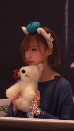 a woman holding a white teddy bear in her hands