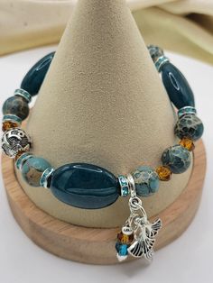 This blue jade just does not photograph well - it is a beautiful shade of teal blue paired here with amber crystal , Emperor Jasper and TIbetan silver.  The look is completed with Silver Prayer bead and dangling feminine charms. Jade is the symbol of serenity, purity, harmony and health. Companion pieces, stackables and custom available by contacting Teresa:) Blue Jade Spiritual Bracelets, Spiritual Blue Jade Bracelets, Blue Jade Beaded Bracelet For Healing, Blue Jade Beaded Bracelets For Healing, Handmade Blue Jade Beaded Bracelets, Handmade Blue Jade Beaded Bracelet, Blue Beaded Jade Bracelets, Blue Jade Bracelets For Healing, Blue Jade Bracelets With Natural Stones