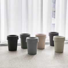 five cups are lined up in front of a window