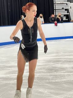 a woman skating on an ice rink wearing short shorts and knee high boots with her hands behind her back