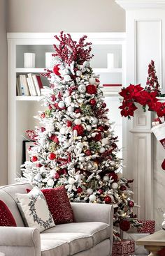 a living room decorated for christmas with red and white decorations on the tree, couches and fireplace