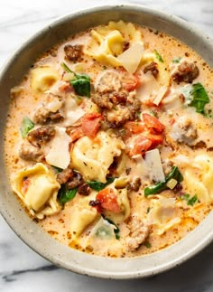 a bowl filled with pasta, meat and vegetables on top of a marble countertop