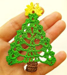 a crocheted christmas tree ornament being held in someone's hand