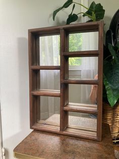 a wooden shelf sitting on top of a table next to a potted green plant