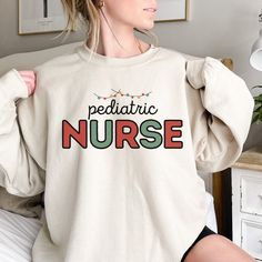 a woman wearing a sweatshirt with the word nurse printed in multicolored letters on it