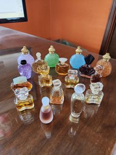 an assortment of perfume bottles sitting on top of a wooden table