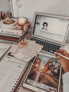 an open laptop computer sitting on top of a desk next to a pile of books