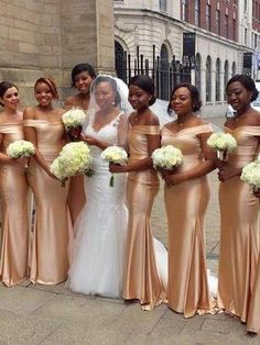 a group of bridesmaids in gold dresses posing for a photo on the street