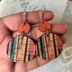 a pair of earrings that are made out of wood and painted with multicolored stripes