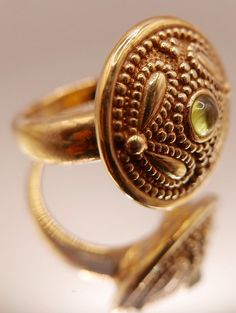 Vintage 14 carat gold Etruscan Revival ring with bezel set peridot gemstone and ornate granulation on medallion style head. Beautiful artisan piece with exquisite attention to detail including etching on underside of head.  Stamped 14K Excellent vintage condition Ring size: US 7 Head diameter: 2.2 cm / 0.7 inch Weight: 2.46 grams ☞ Please view my shipping and sales policies and ✎ Contact me with questions prior to purchase...all sales are final. http://www.etsy.com/shop/Andeebird/policy Gold Byzantine Jewelry With Cabochon, Byzantine Gold Cabochon Jewelry, Byzantine Gold Jewelry With Cabochon, Luxury Gold Peridot Jewelry, Luxury Gold Jewelry With Peridot, Elegant Round Peridot Stone Jewelry, Byzantine Gemstone Jewelry For Weddings, Elegant Peridot Round Jewelry, Byzantine Style Round Gemstone Jewelry