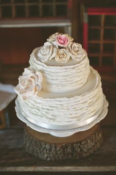 a wedding cake with white frosting and pink flowers on top sitting on a table